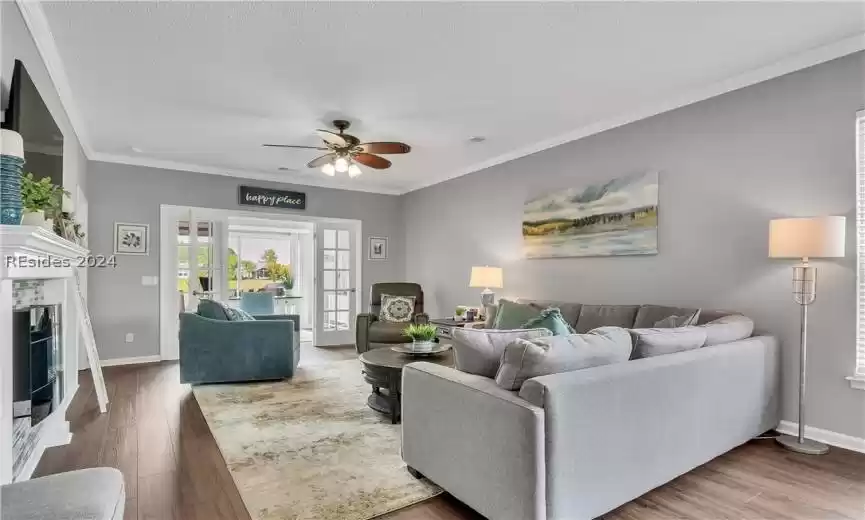 Living room featuring crown molding, wood-type flooring, ceiling fan, and a textured ceiling