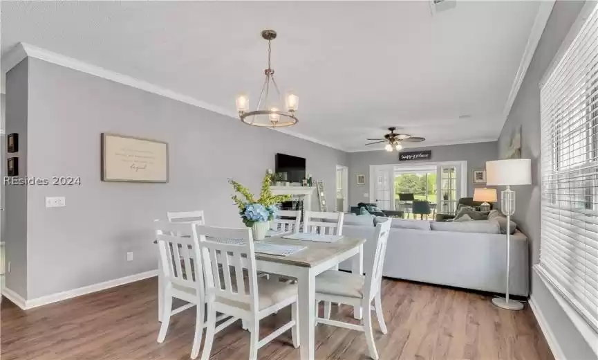 Dining space featuring ceiling fan with notable chandelier, crown molding, and wood-type flooring