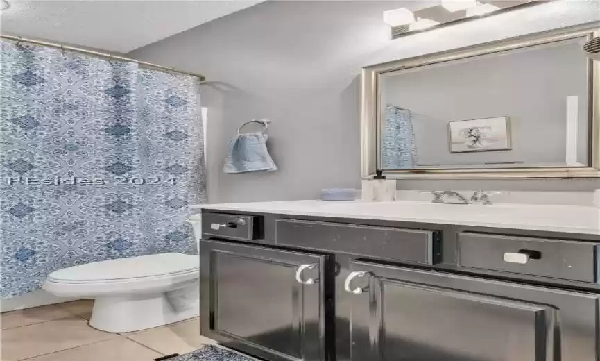 Bathroom featuring a textured ceiling, vanity, toilet, and tile flooring