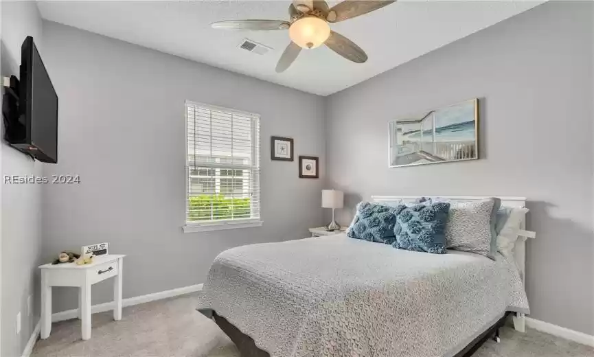 Carpeted bedroom with ceiling fan and a textured ceiling