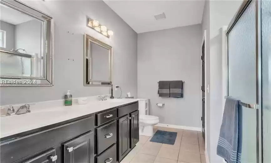 Bathroom with toilet, tile flooring, a textured ceiling, and double sink vanity