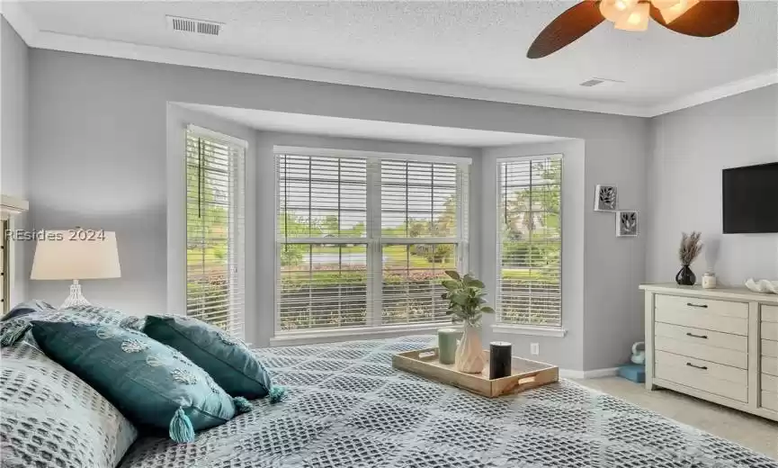 Bedroom featuring ornamental molding, light colored carpet, ceiling fan, and a textured ceiling