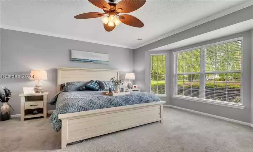 Carpeted bedroom featuring ornamental molding, ceiling fan, and a textured ceiling