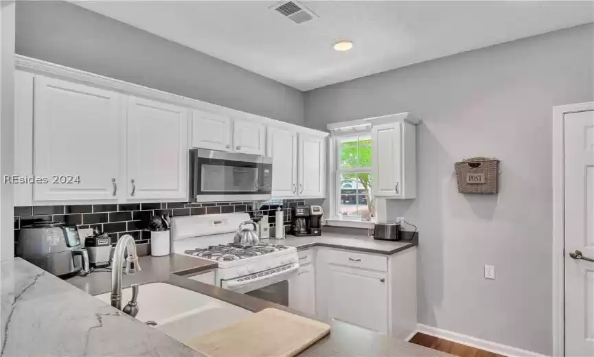 Kitchen featuring white cabinets, white gas range oven, and hardwood / wood-style floors