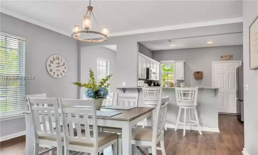 Dining space with plenty of natural light, a chandelier, and dark hardwood / wood-style floors