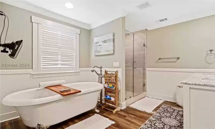 Primary Bathroom featuring ornamental molding, vanity, separate shower and tub, and hardwood / wood-style floors