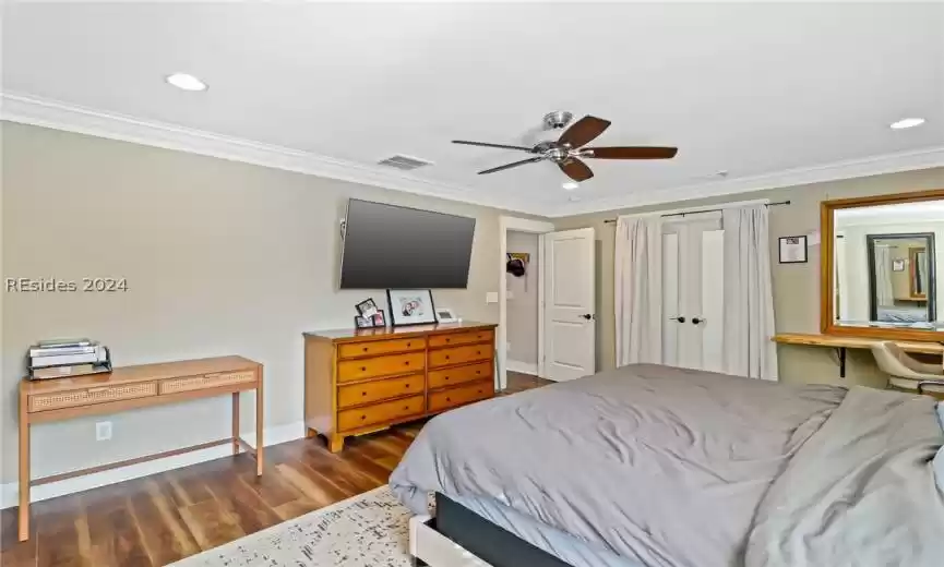 Primary Bedroom featuring ceiling fan, dark wood-type flooring, and ornamental molding