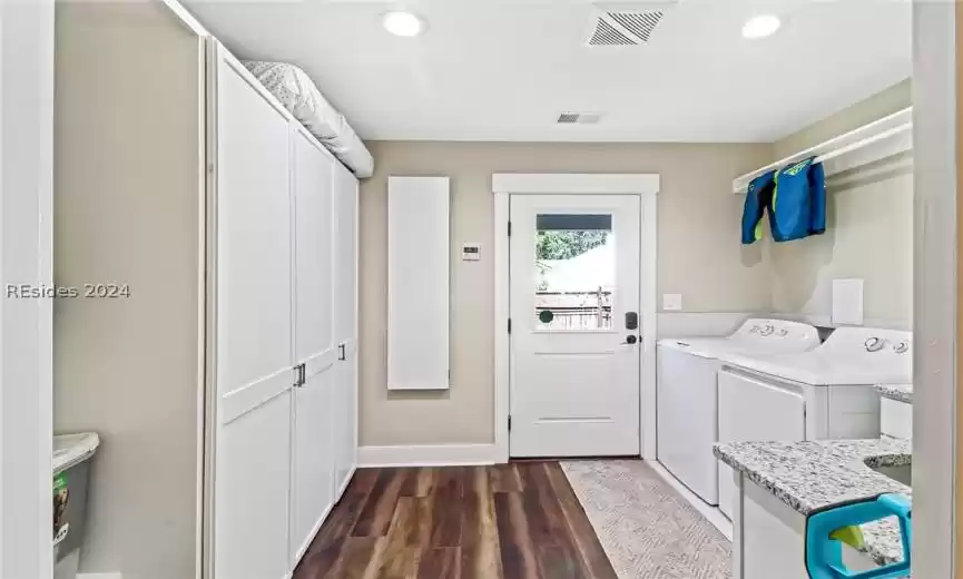 Laundry room with cabinets, dark wood-type flooring, and washer and dryer