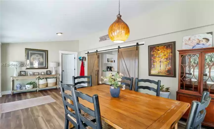 Dining space with lofted ceiling, dark hardwood / wood-style flooring, and a barn door