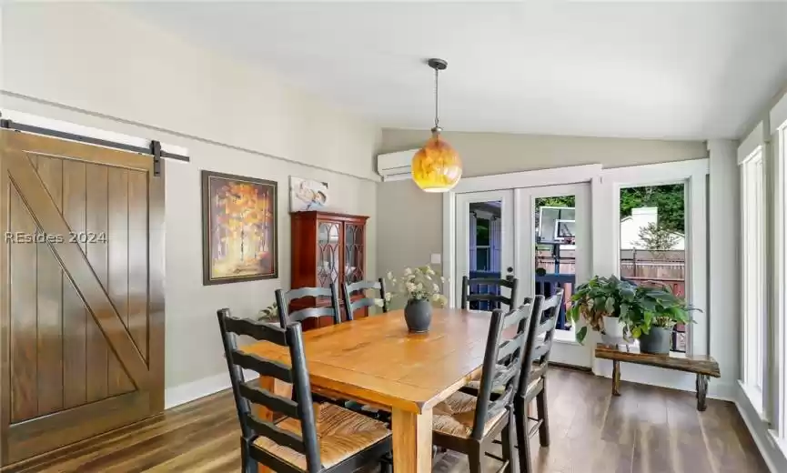 Dining space with vaulted ceiling, a barn door, and dark hardwood / wood-style floors