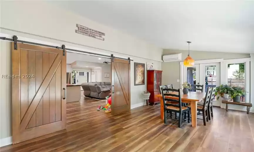 Dining area featuring lofted ceiling, dark wood flooring, and a barn door