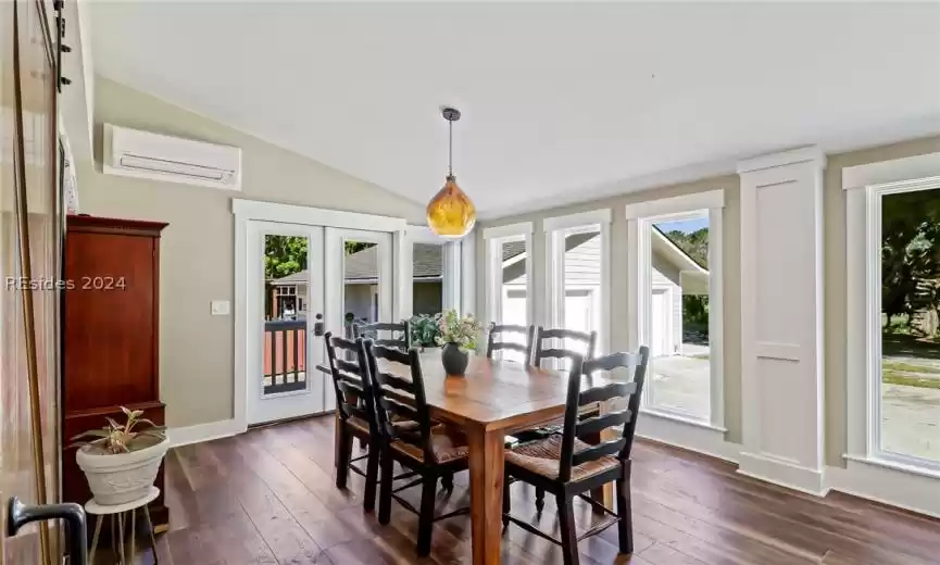 Dining room with lofted ceiling, plenty of natural light, dark hardwood / wood-style floors, and a wall mounted AC