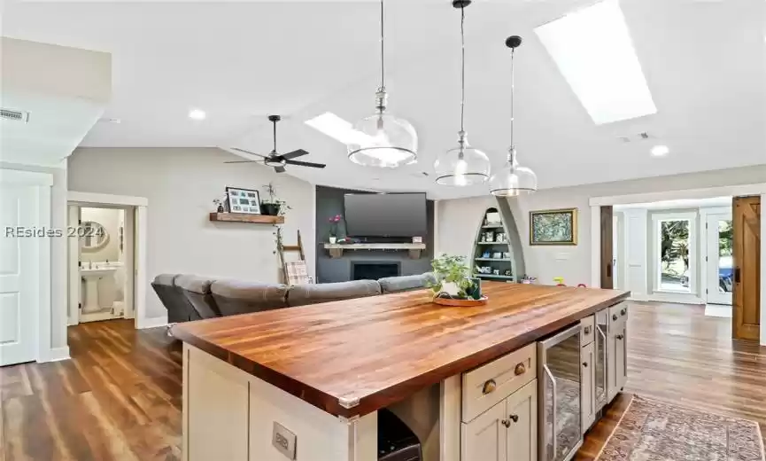 Kitchen featuring decorative light fixtures, butcher block counters, ceiling fan with notable chandelier, dark wood-type flooring, and a center island