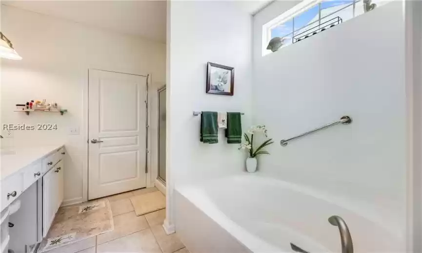 Primary bathroom with soaking tub and walk in shower and brightened by a transom window
