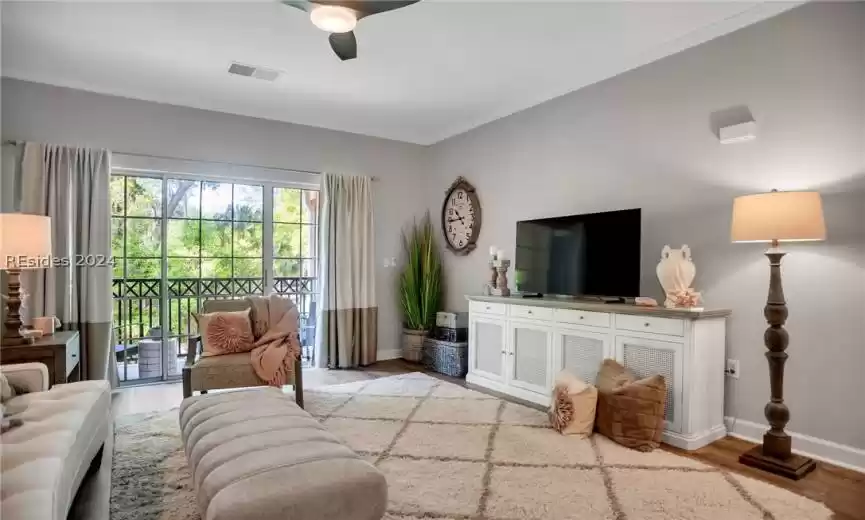 Living room with crown molding, ceiling fan, and light wood-type flooring