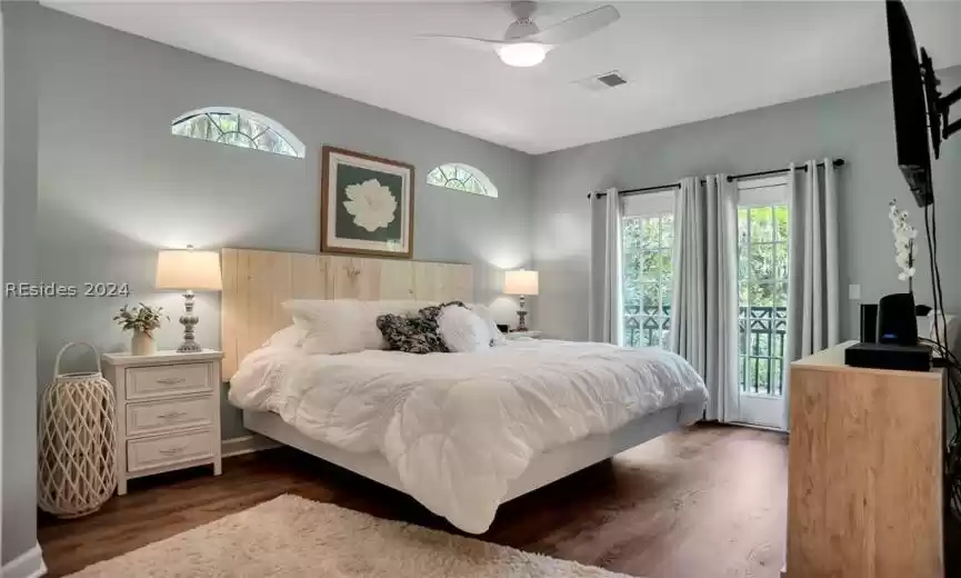 Bedroom with dark hardwood / wood-style flooring, ceiling fan, and access to exterior