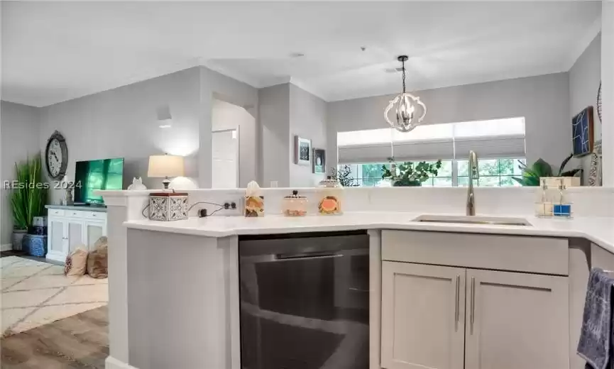 Kitchen with hanging light fixtures, light hardwood / wood-style floors, dishwasher, sink, and ornamental molding