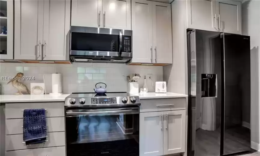 Kitchen featuring appliances with stainless steel finishes, wood-type flooring, and tasteful backsplash