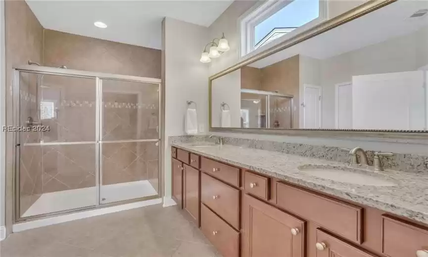 Primary bathroom with dual vanities and tile shower with bench seat.