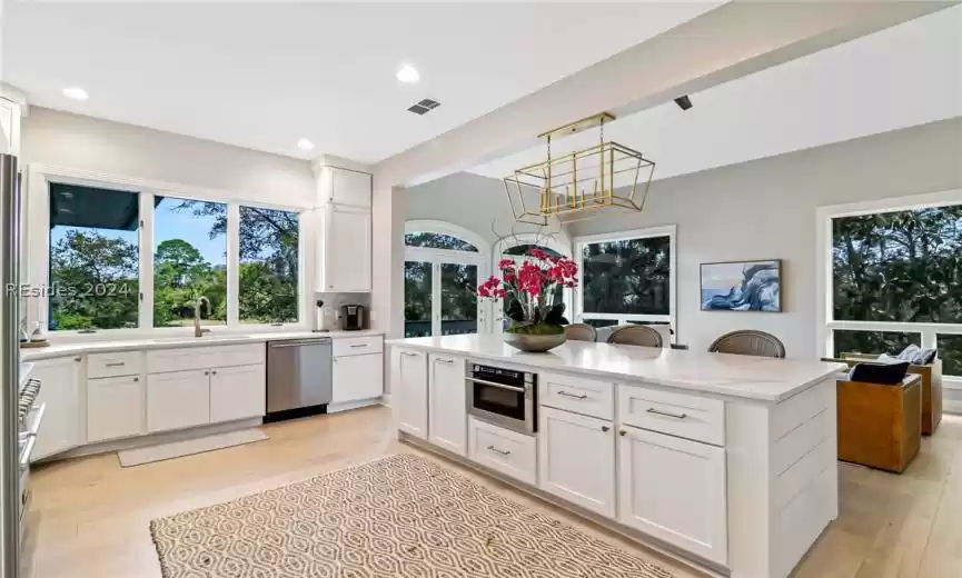 Kitchen with decorative light fixtures, white cabinetry, a chandelier, and stainless steel appliances