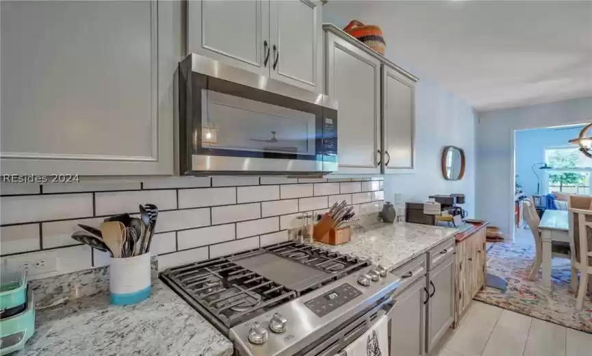 Kitchen with light stone counters, backsplash, and stainless steel appliances