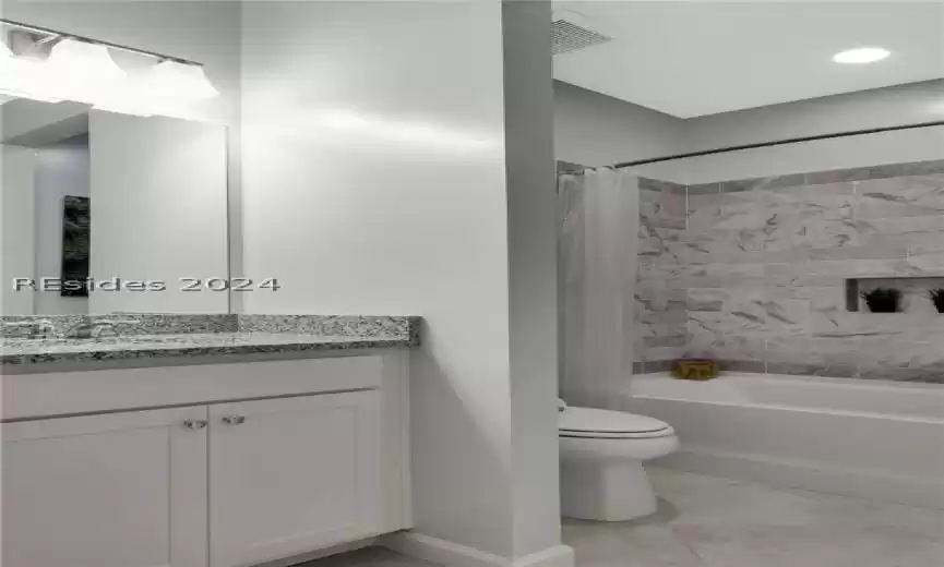 Full bathroom with vanity with extensive cabinet space, toilet, tile flooring, and shower / tub combo with curtain