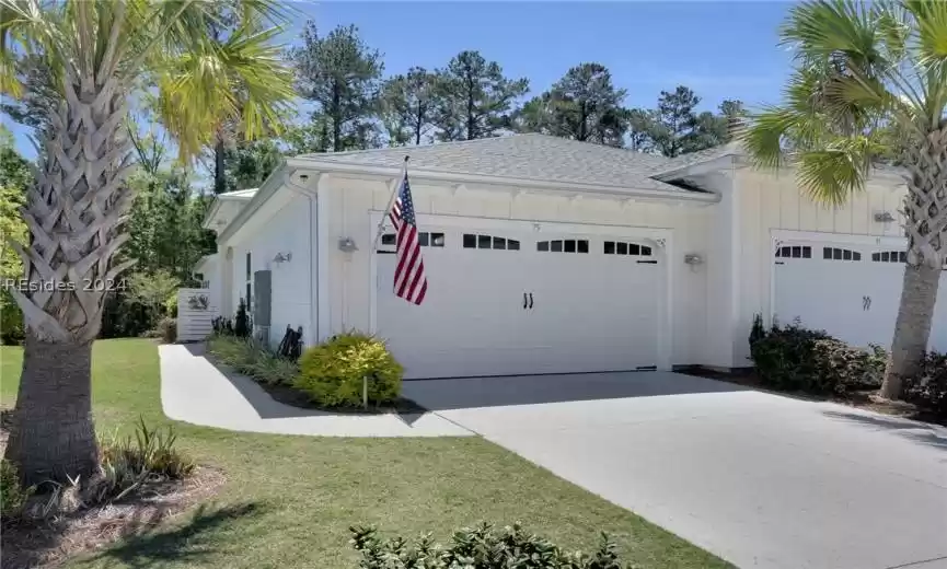 View of side of property featuring a garage and a lawn