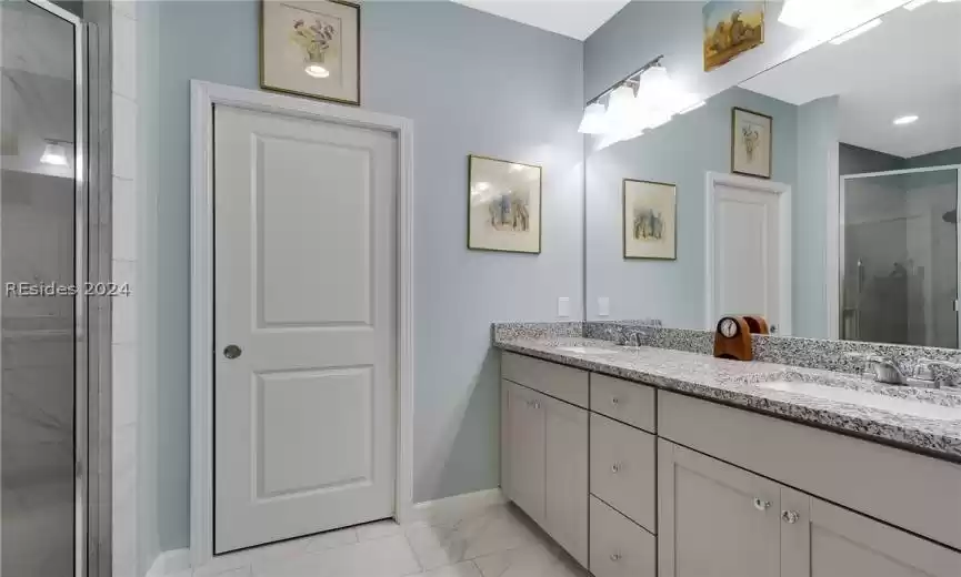 Bathroom with tile flooring, oversized vanity, an enclosed shower, and dual sinks