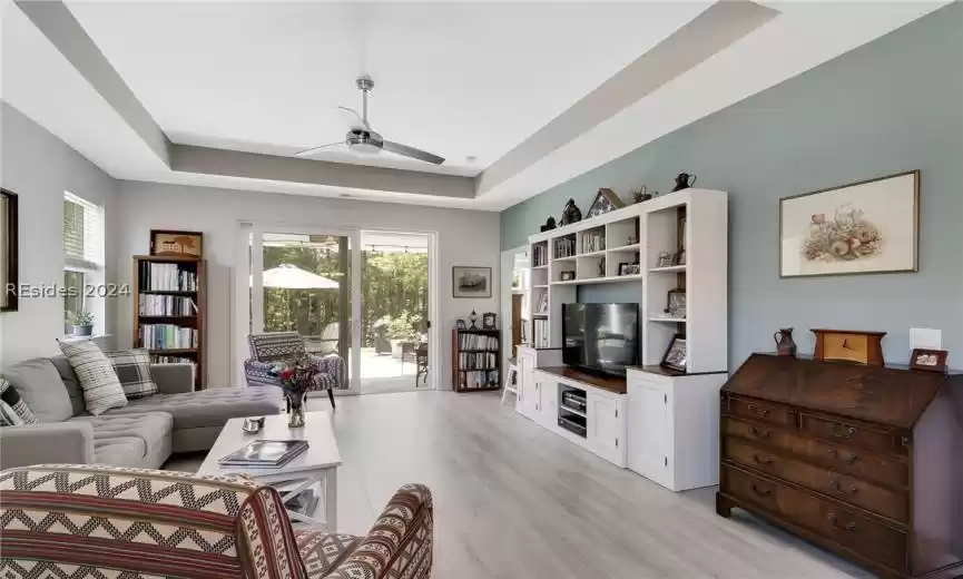 Living room with light hardwood / wood-style flooring, a wealth of natural light, and a raised ceiling