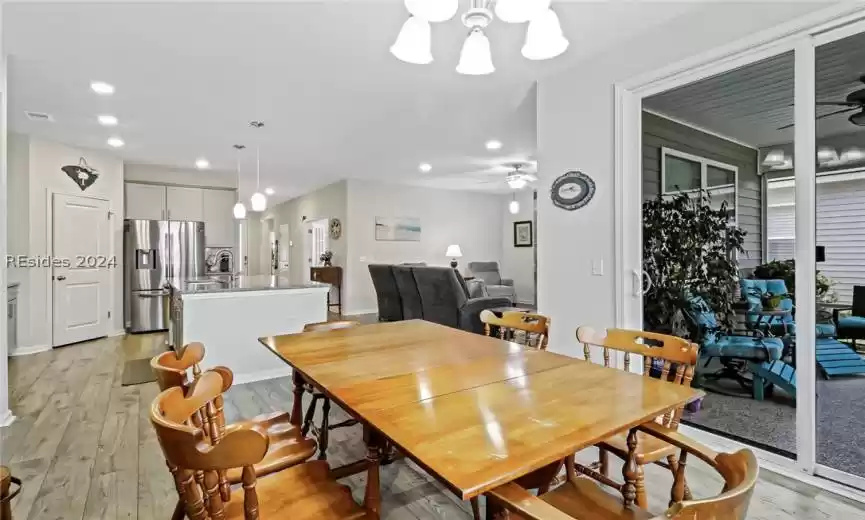 Dining area featuring sink, light hardwood / wood-style floors, and ceiling fan with notable chandelier