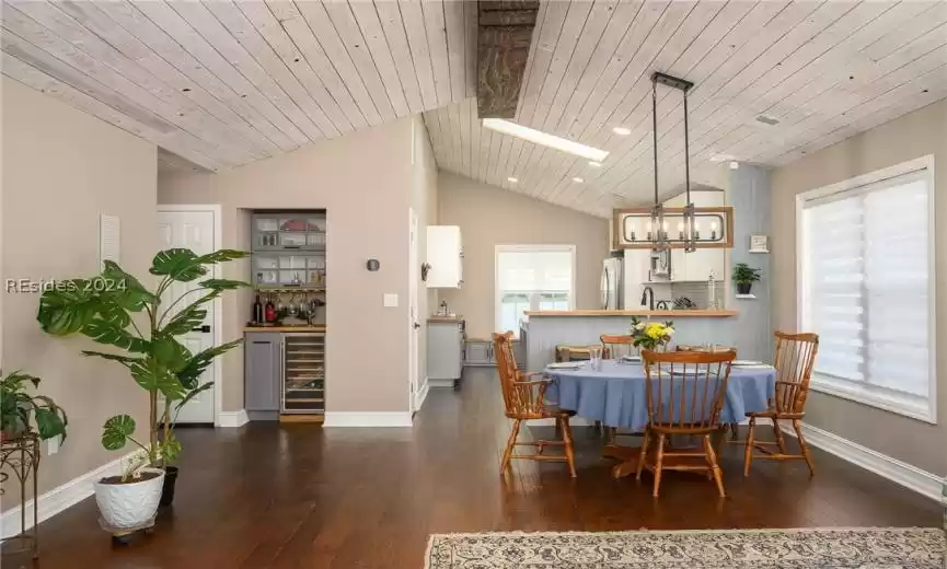 Dining space featuring bar area, dark hardwood / wood-style flooring, lofted ceiling with skylight, an inviting chandelier, and wood ceiling