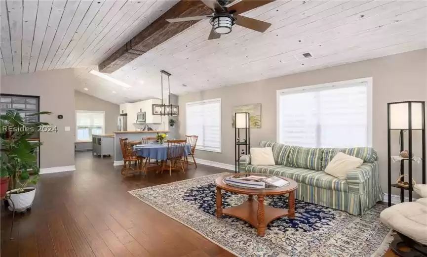 Living room featuring lofted ceiling with beams, wooden ceiling, wood-type flooring, and ceiling fan