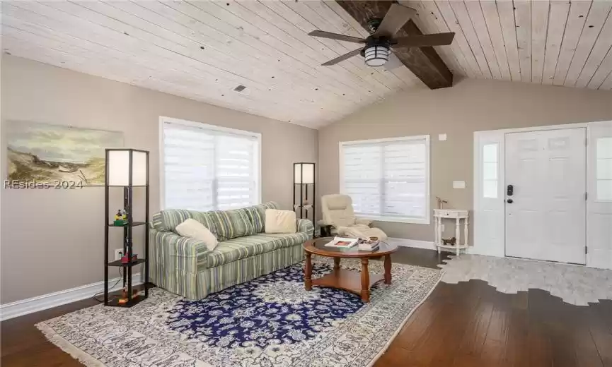 Living room with wood ceiling, lofted ceiling with beams, ceiling fan, and hardwood / wood-style floors