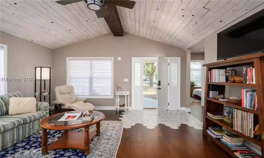 Living room featuring hardwood / wood-style flooring, wood ceiling, ceiling fan, and vaulted ceiling with beams