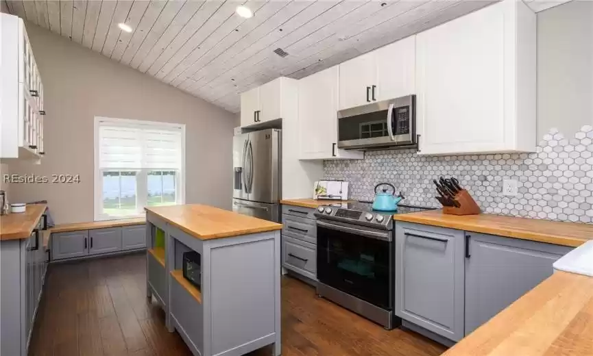 Kitchen featuring butcher block countertops, appliances with stainless steel finishes, gray cabinets, and dark wood-type flooring