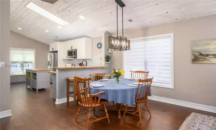 Dining room featuring wooden ceiling, a notable chandelier, dark hardwood / wood-style floors, and vaulted ceiling with skylight