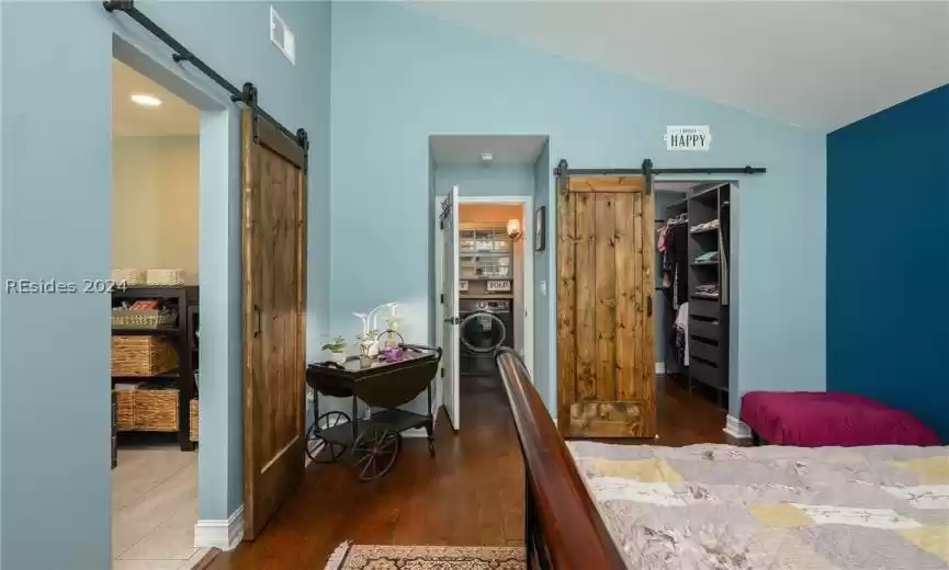 Primary bedroom with view of ensuite, convenient laundry, and primary closet with barndoor